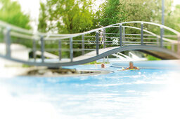 Eine Brücke aus Metall führt über ein Aussenschwimbecken der Terme in Bad Birnbach.