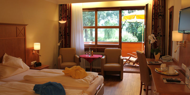 Komfort Doppelzimmer mit Balkonblick und gemütlicher Sitzgelegenheit vor dem Fenster im Quellenhof.