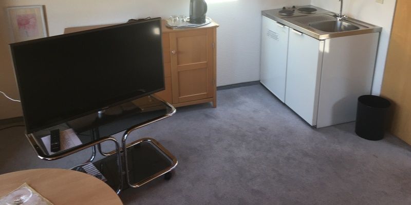 Ein heller Raum im Studio Westlage mit TV, Kühlschrank und Spüle.