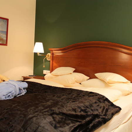 Schlafzimmer der Juniorsuite Südlage mit einem komfortablen Bett und zwei stilvollen Nachttischlampen.