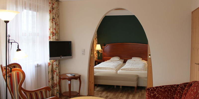 Ein bequemer Sessel neben dem Nachttisch im Schlafzimmer der Senioren Suite Südlage im Hotel Quellenhof.