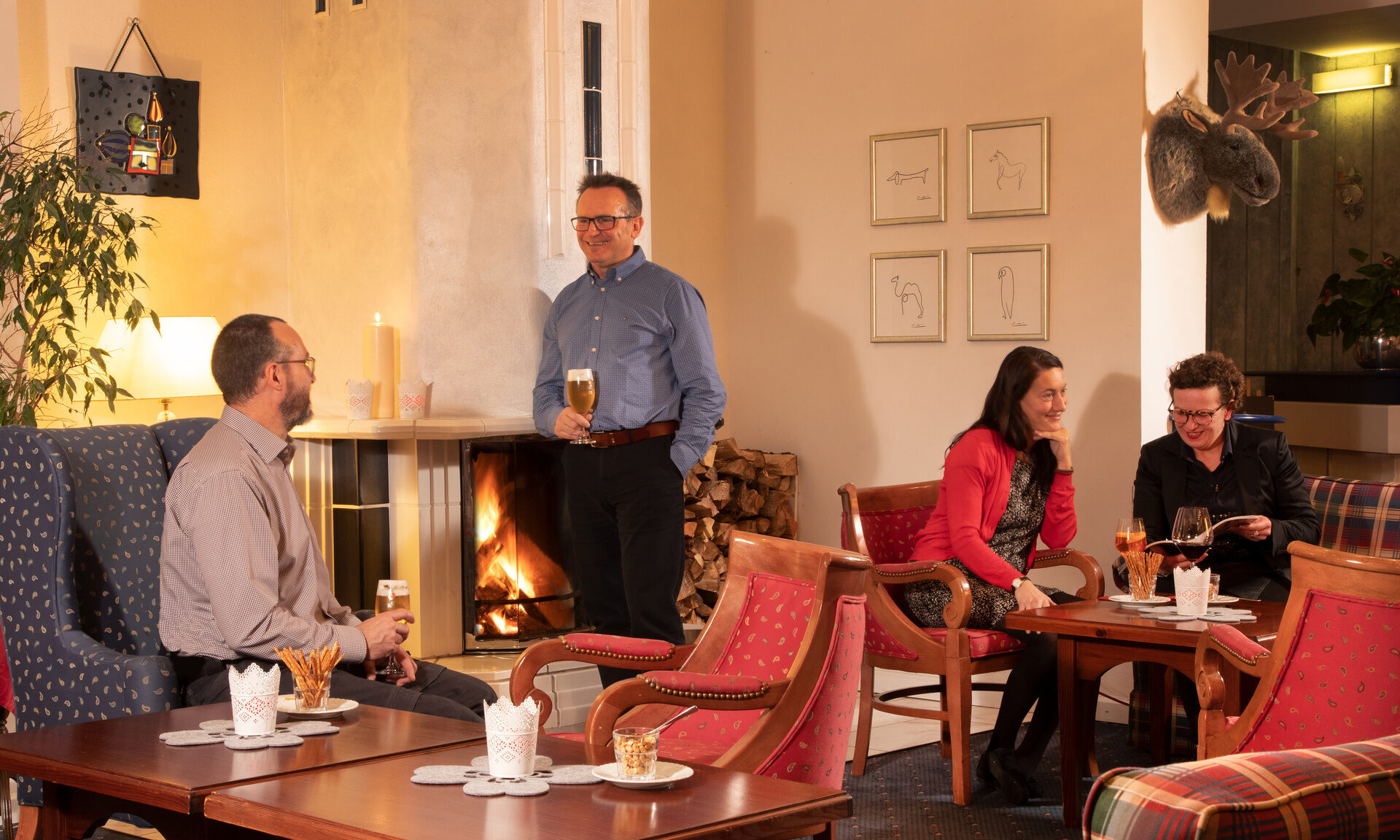 Gemütlicher Gästeabend in der Lobby des Hotel Quellenhof, mit Getränken und Gesprächen vor dem brennenden Kamin.