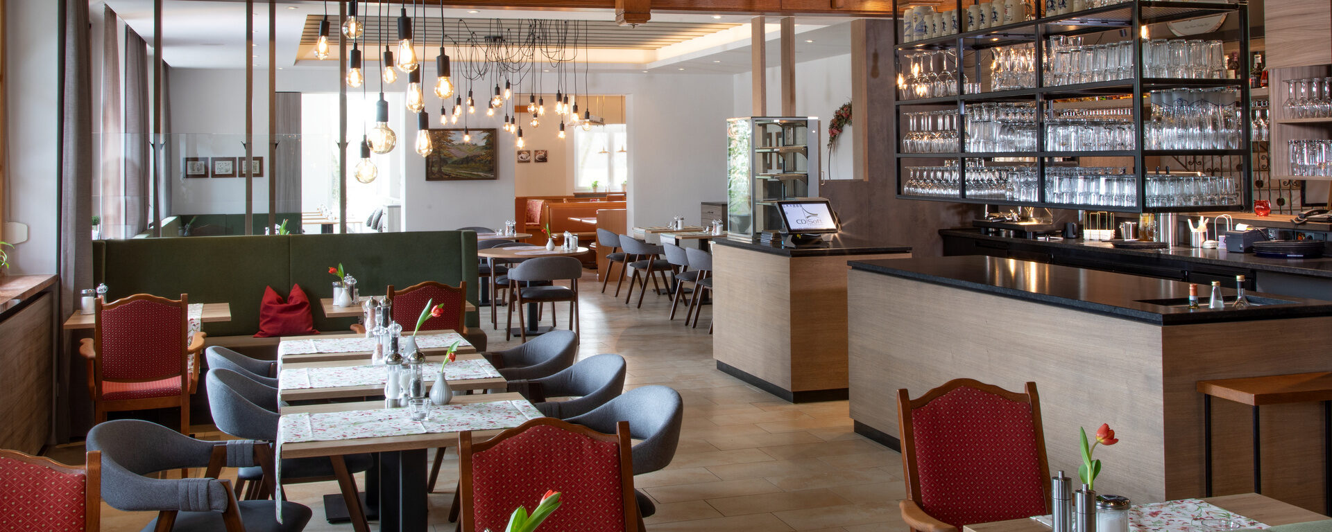 Der stilvoll eingerichtete Speiseraum im Hotel Quellenhof, mit Tischen, Stühlen und einer Theke.