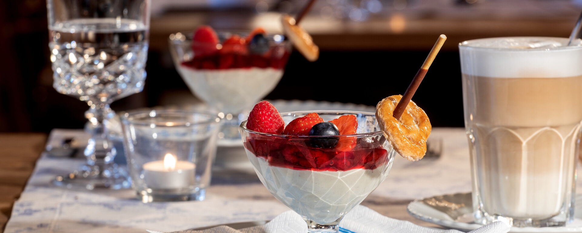 Appetitlich angerichtete Desserts mit einem Glas Latte Macchiato im Restaurant des Hotel Quellenhof.
