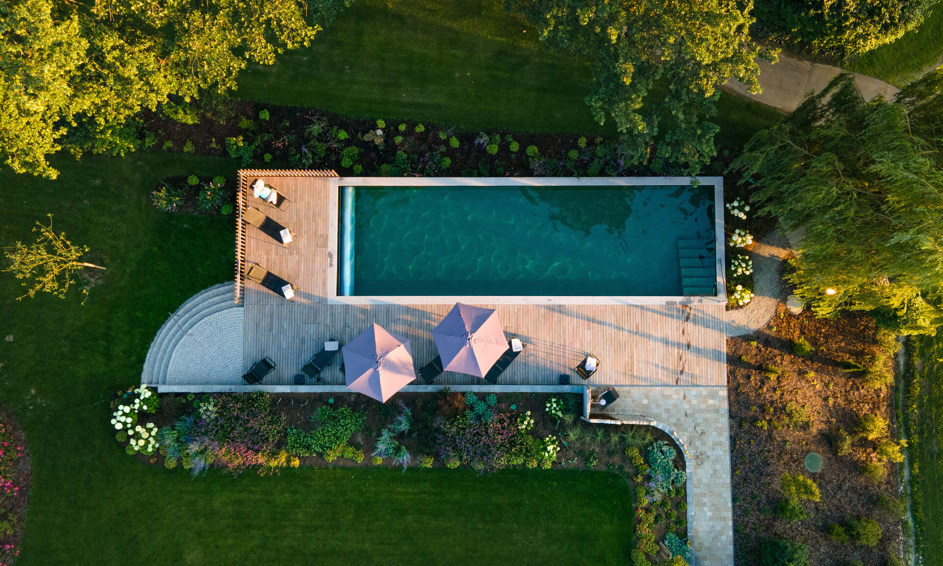 Vogelperspektive des Naturpools und Terrasse mit Sonnenschirmen im Hotel Quellenhof.