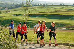 Eine Gruppe von Leuten beim Nordic Walking durch die grüne malerische Landschaft des Rottals nahe Bad Birnbach.